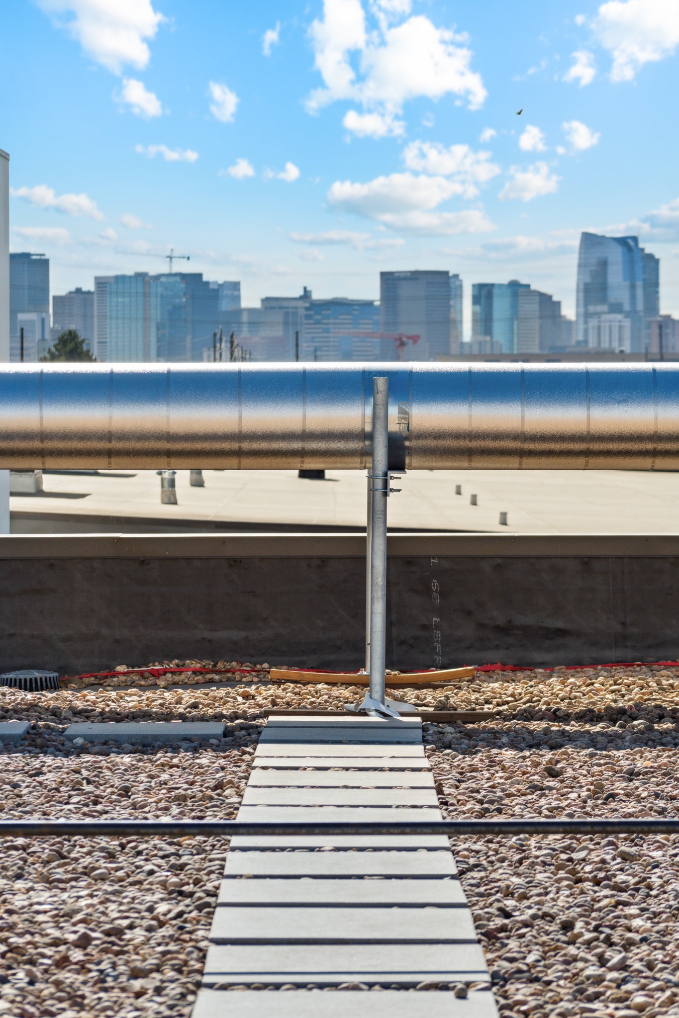 Rooftop cooling-system piping with the Denver skyline beyond